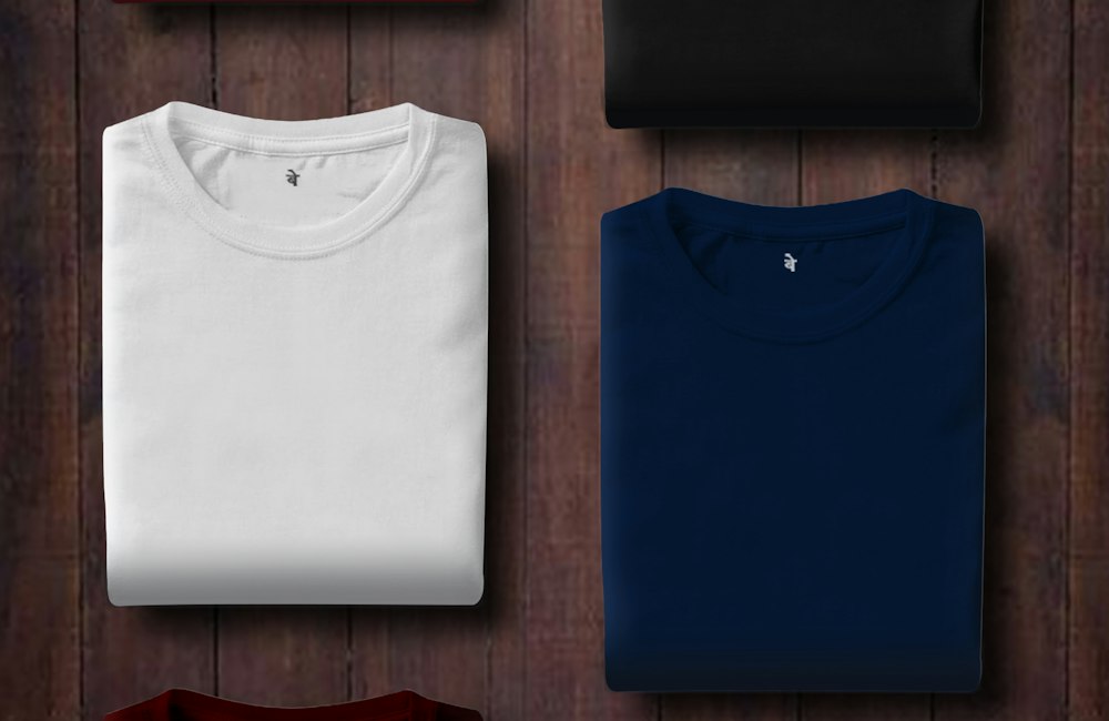 Folded cotton T-shirts in white, black, navy and red seen from above