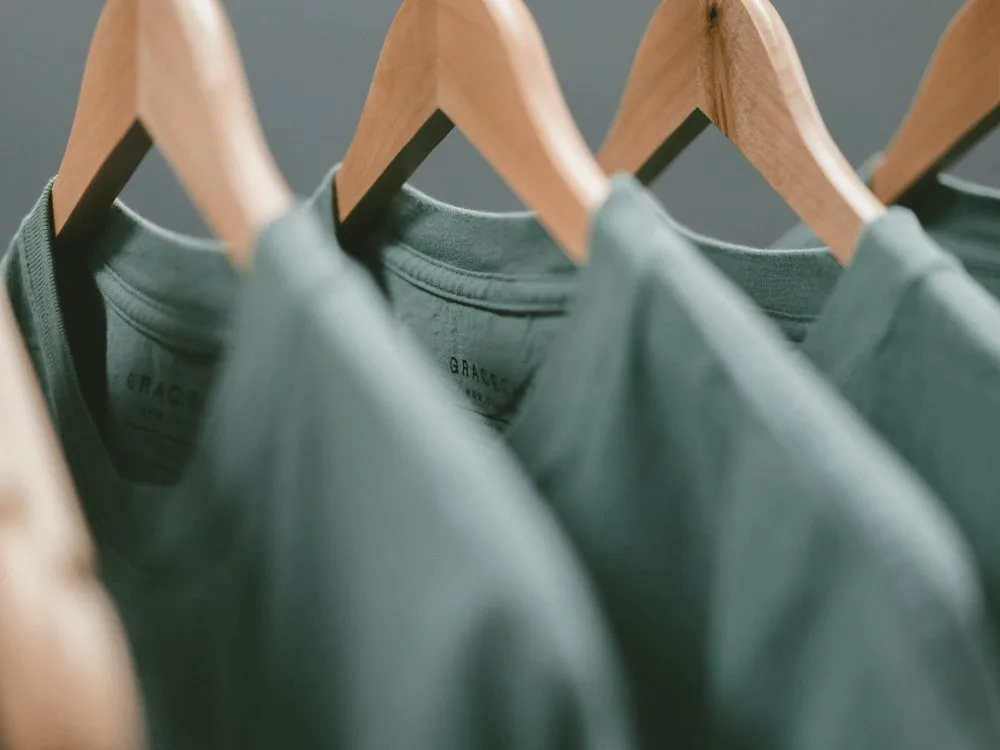 Green cotton T-shirts on wooden hangers