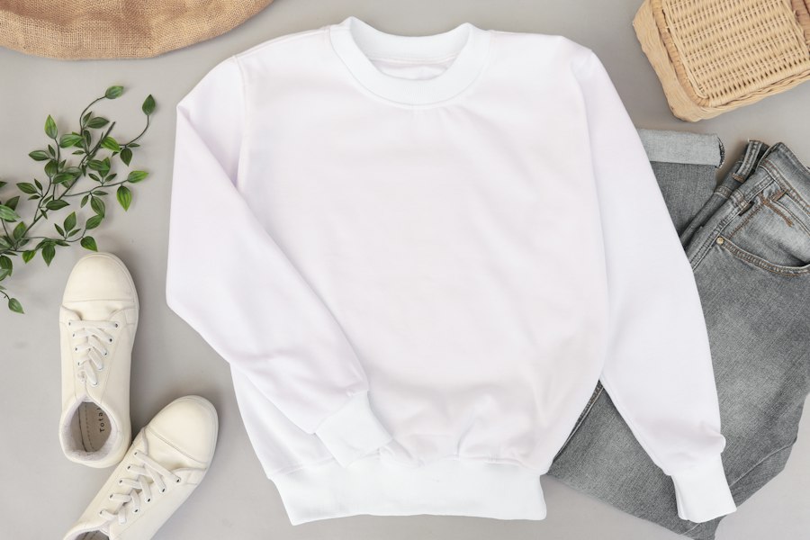White cotton sweatshirt laid flat next to sneakers and a plant